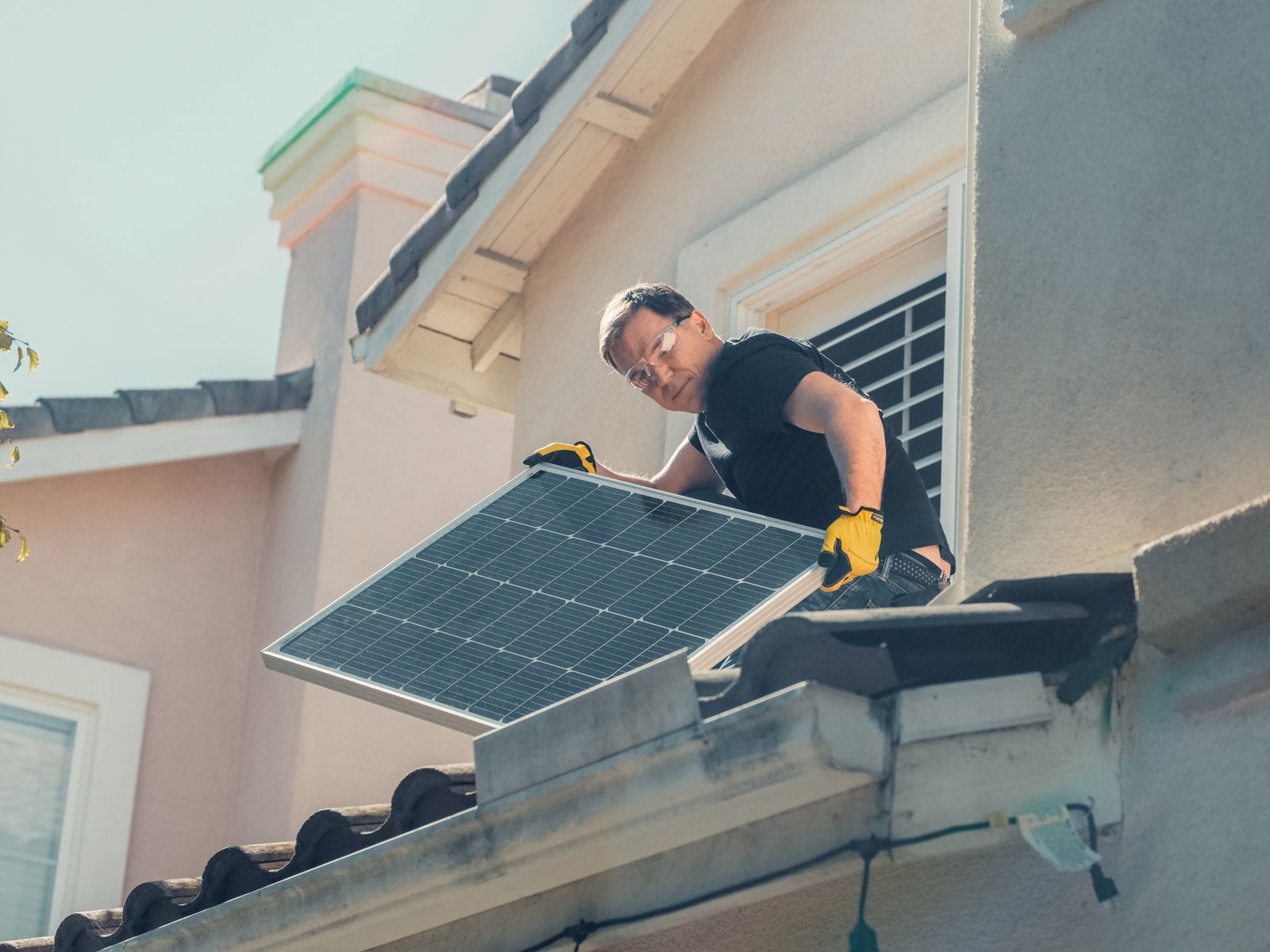 Installer fitting a solar panel on the roof of a house