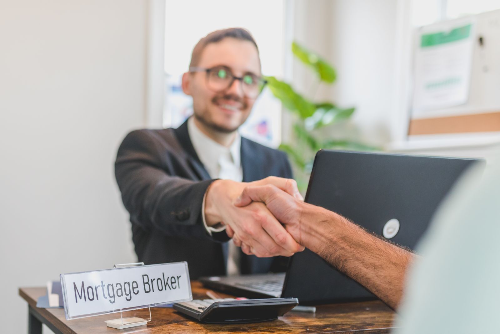 Loan officer shaking hands with a couple across a desk