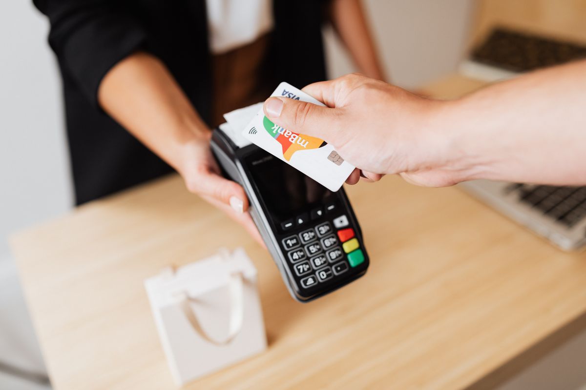 Customer tapping a card on a payment terminal at a shop counter